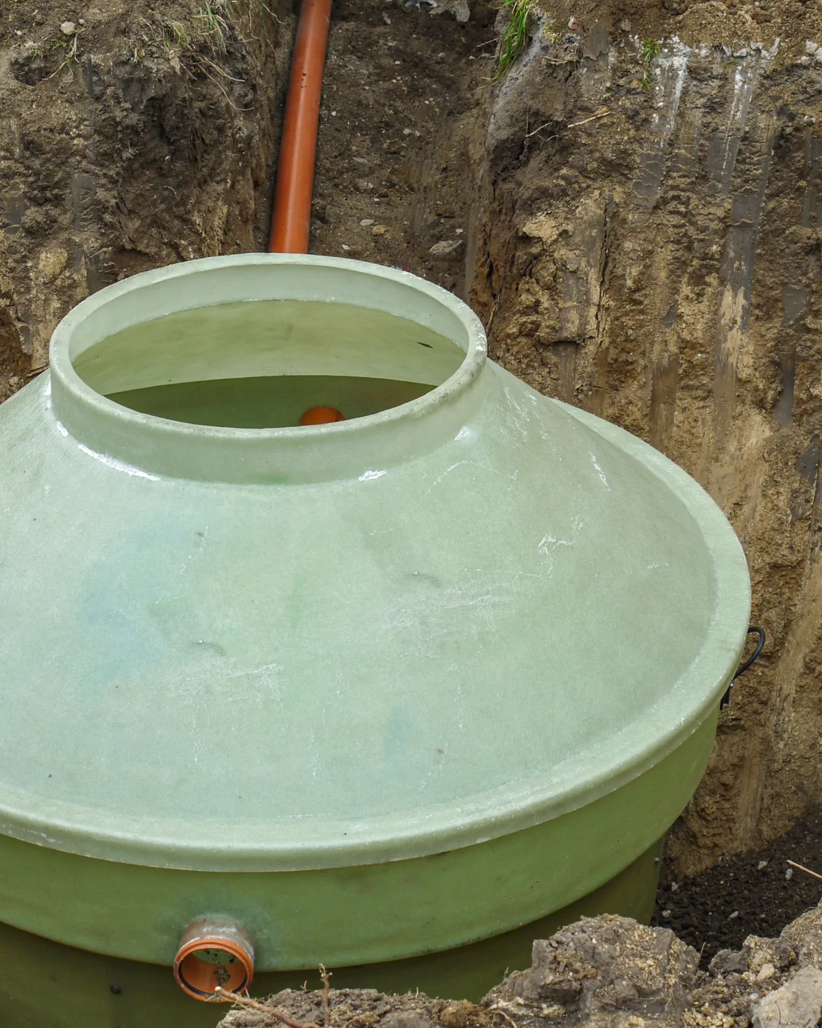 Green septic tank set in a freshly dug hole