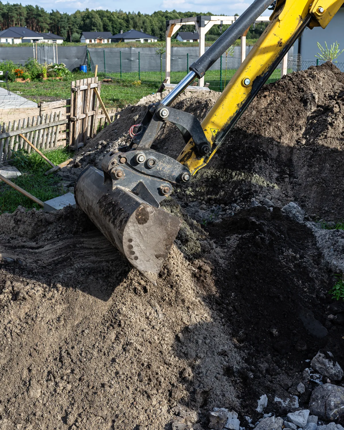 Excavator digging beside a septic tank next to a house